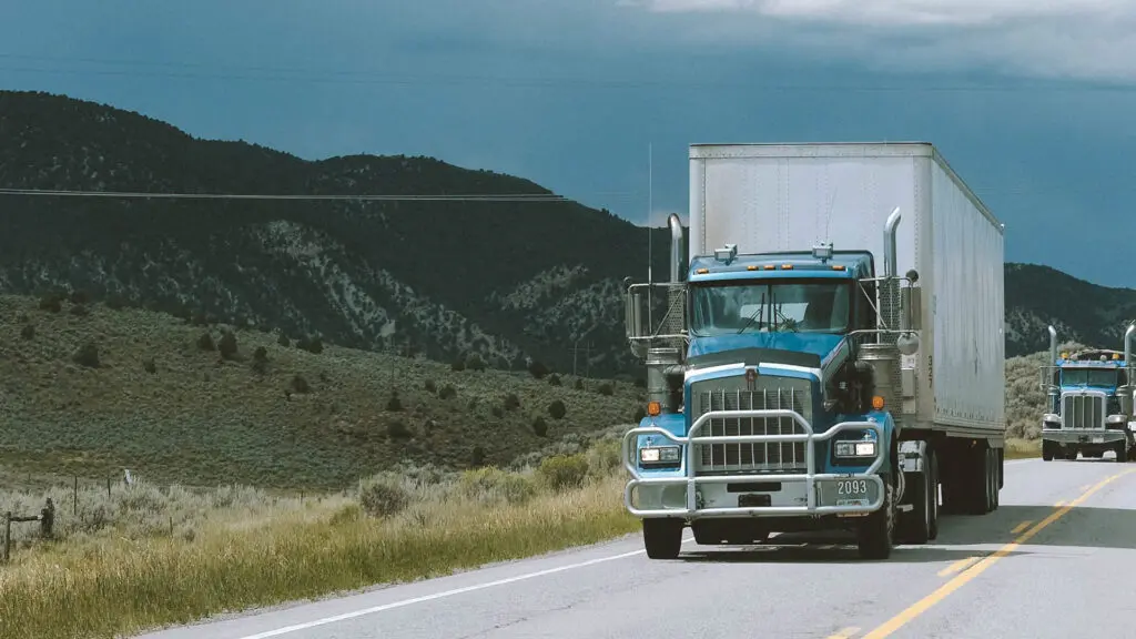 A blue truck is driving down the road